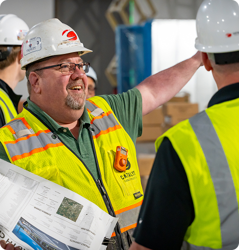 Man in a Catalyst construction hard hat pointing in the direction of something.