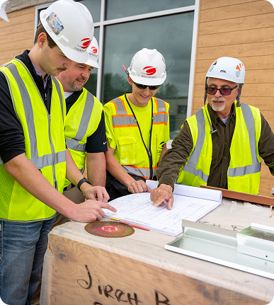 find-your-fit-image A group of four Catalyst Construction contractors looking at architectural plans.