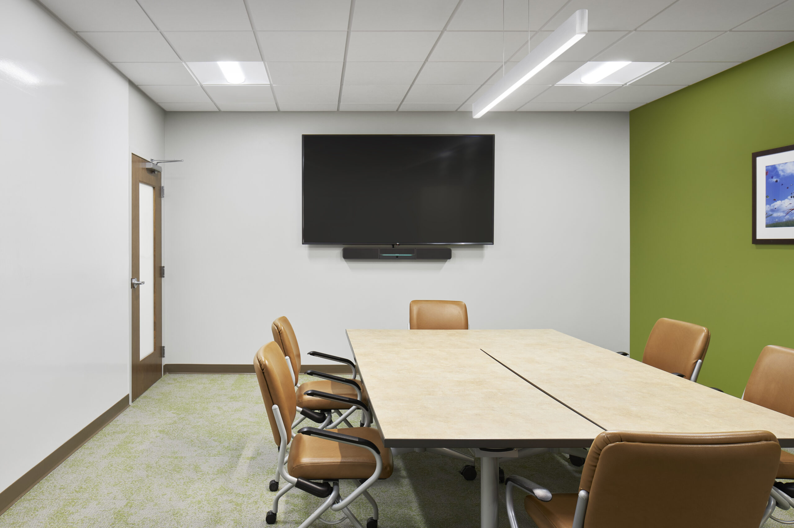 Conference room with a long table, leather rolling chairs, and a tv.