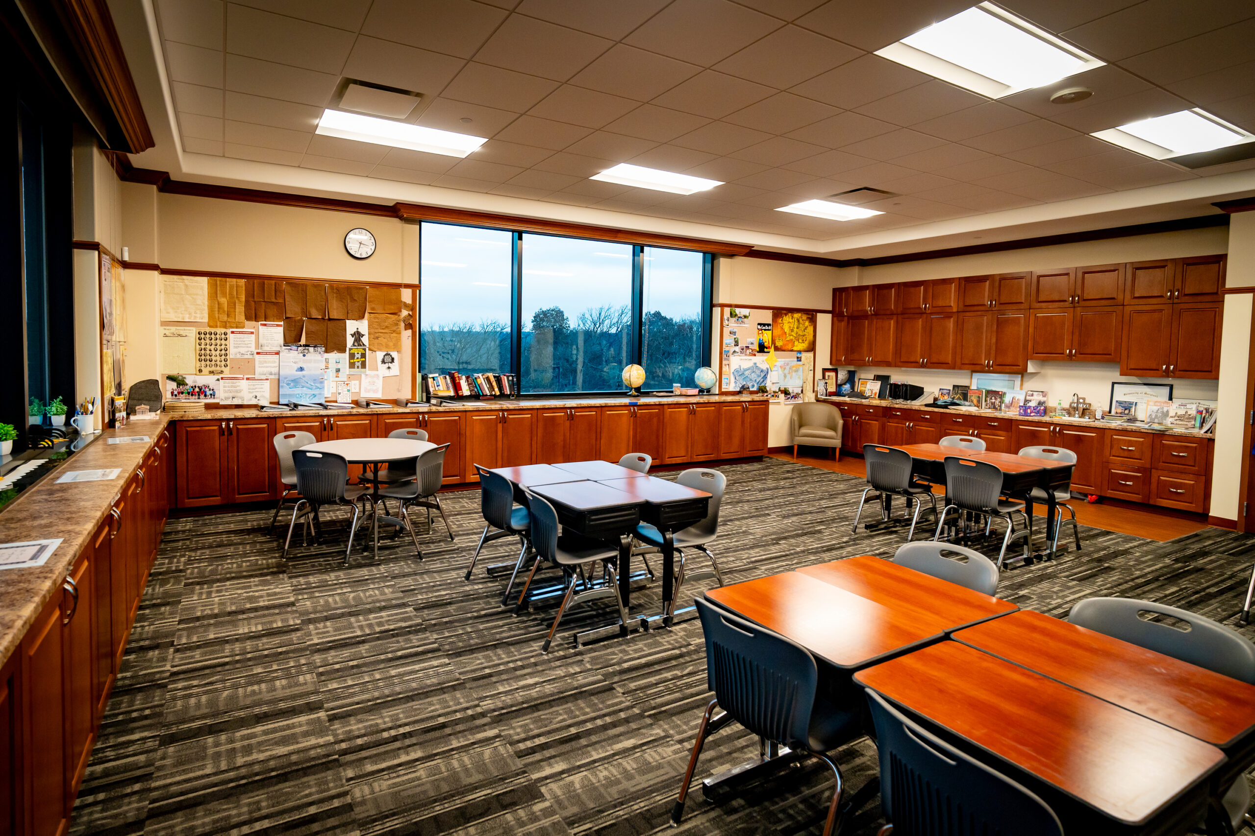 Kids classroom with individual desks, carpeted floors, and lots of cabinets around the perimeter of the classroom.
