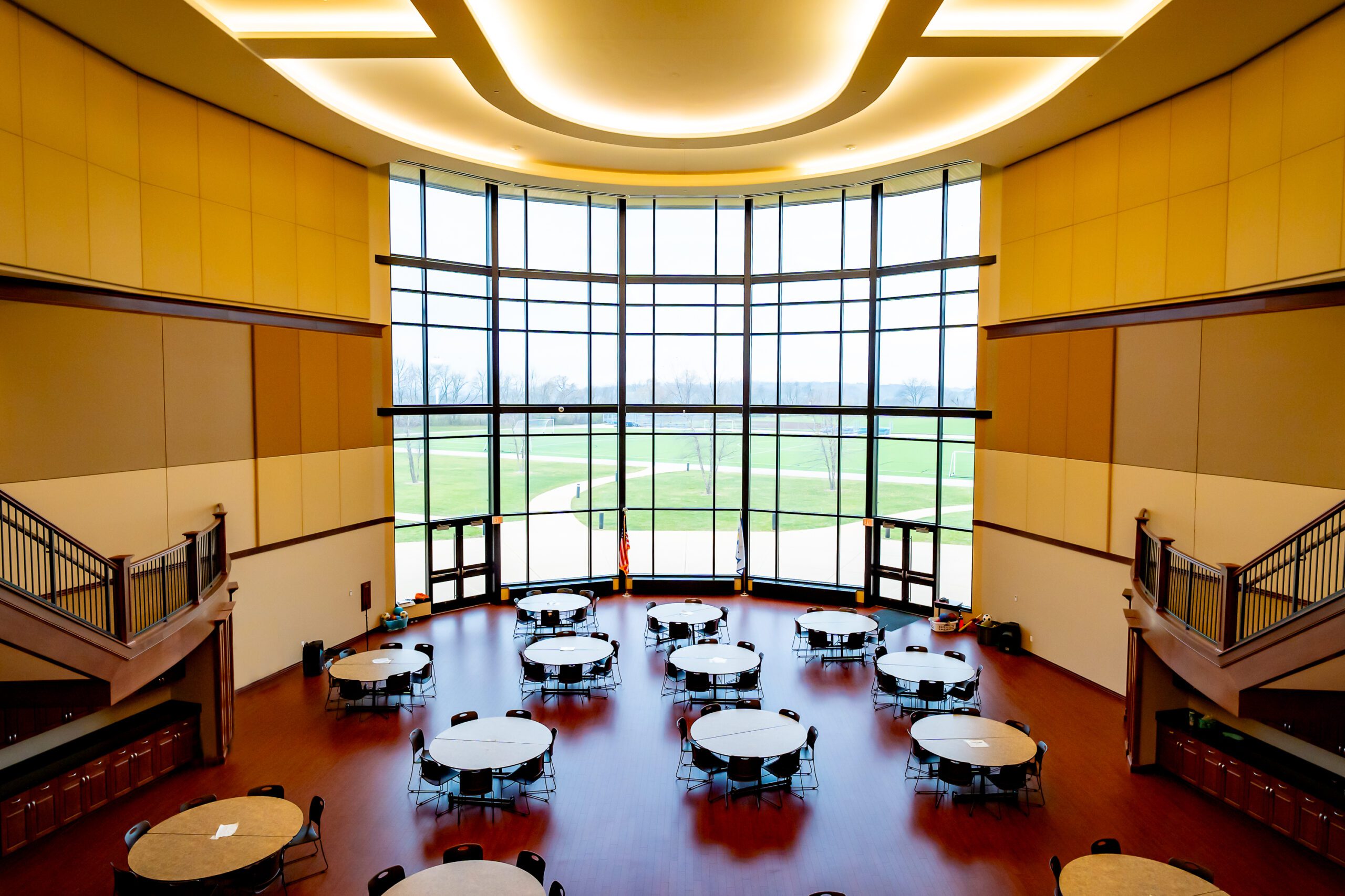 Commons area with multiple round tables overlooking tall windows.